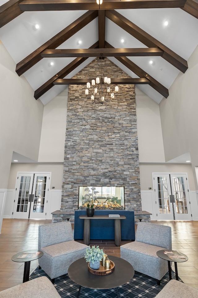 living room with hardwood / wood-style flooring, french doors, high vaulted ceiling, and an inviting chandelier