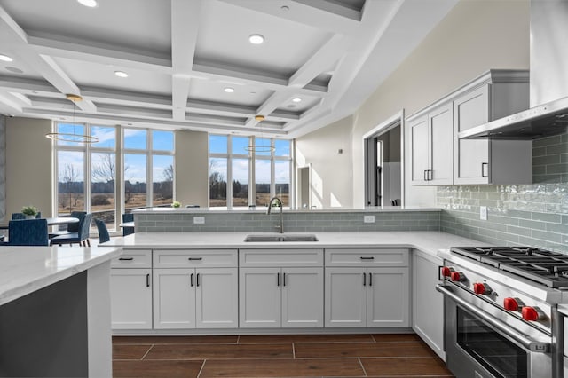 kitchen with coffered ceiling, luxury range, sink, wall chimney exhaust hood, and white cabinetry