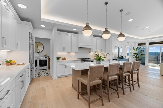 kitchen with a raised ceiling, light hardwood / wood-style flooring, and backsplash