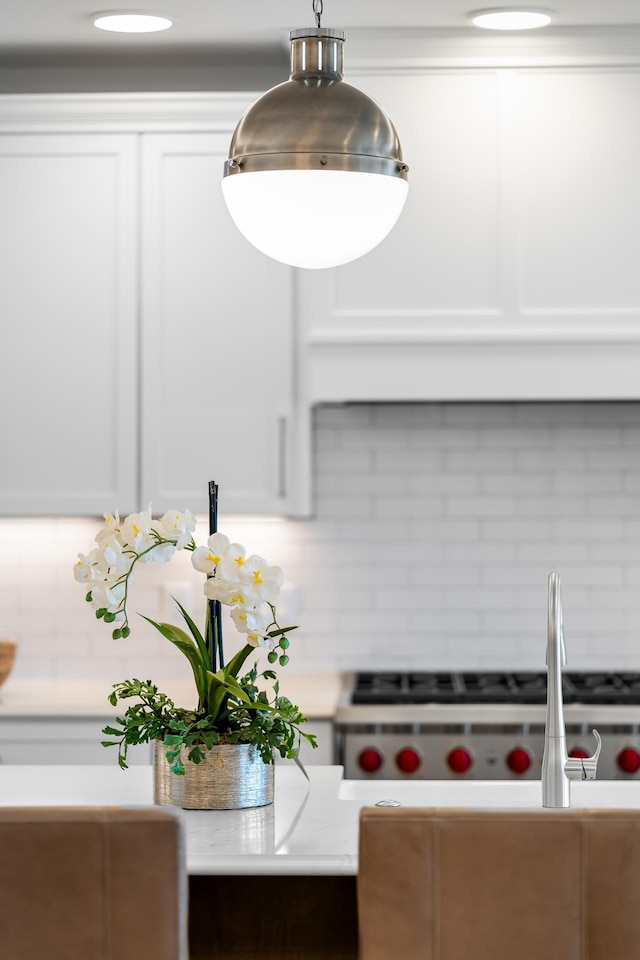 room details featuring white cabinets, hanging light fixtures, and tasteful backsplash