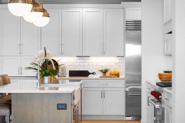 kitchen featuring stainless steel appliances, backsplash, a kitchen bar, white cabinetry, and pendant lighting