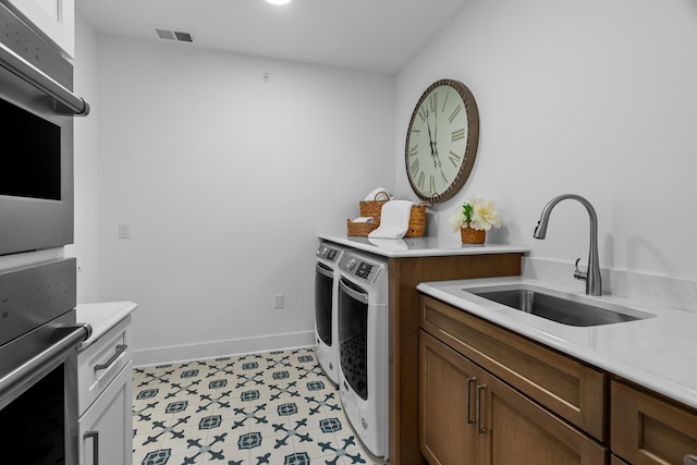 kitchen featuring sink, double wall oven, light tile floors, and washing machine and clothes dryer