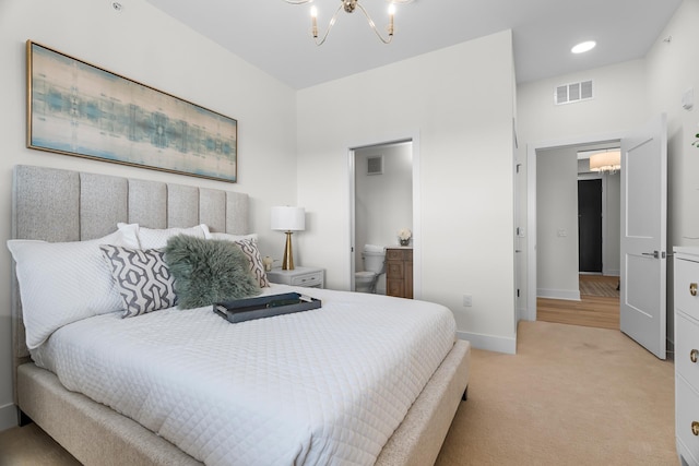 bedroom with a notable chandelier, ensuite bathroom, and light colored carpet