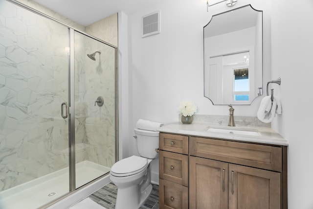 bathroom featuring a shower with shower door, vanity, and toilet