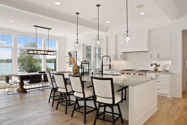 kitchen with a water view, light stone countertops, light hardwood / wood-style floors, and white cabinetry