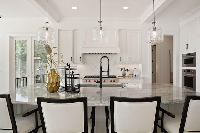 kitchen featuring stainless steel oven, white cabinets, a center island with sink, and light stone counters