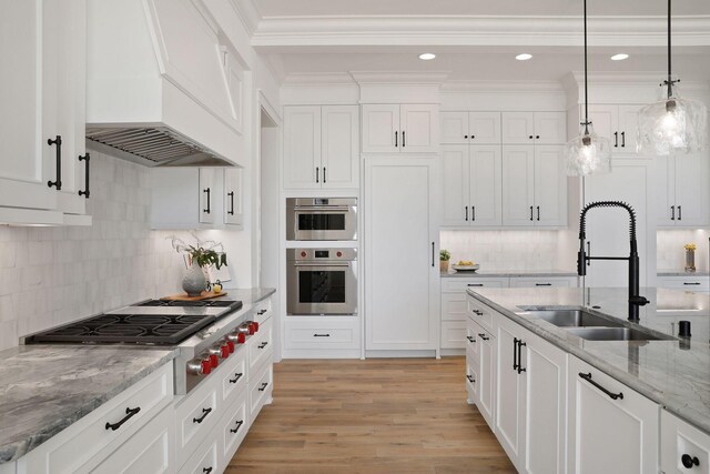 kitchen with custom range hood, pendant lighting, light wood-type flooring, and white cabinetry