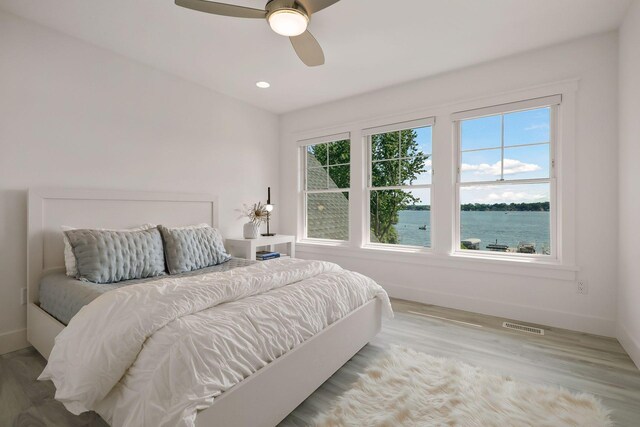 bedroom with a water view, ceiling fan, and hardwood / wood-style flooring