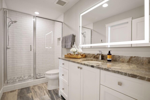 bathroom with walk in shower, vanity, and toilet