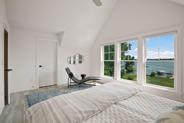 bedroom featuring a water view, ceiling fan, vaulted ceiling, and light hardwood / wood-style flooring