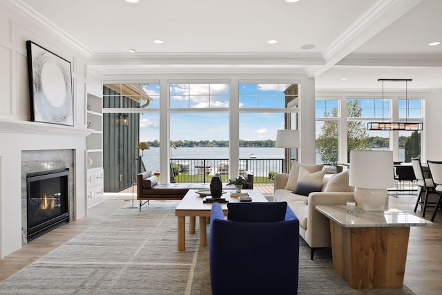 living room featuring light hardwood / wood-style flooring, plenty of natural light, ornamental molding, and a water view