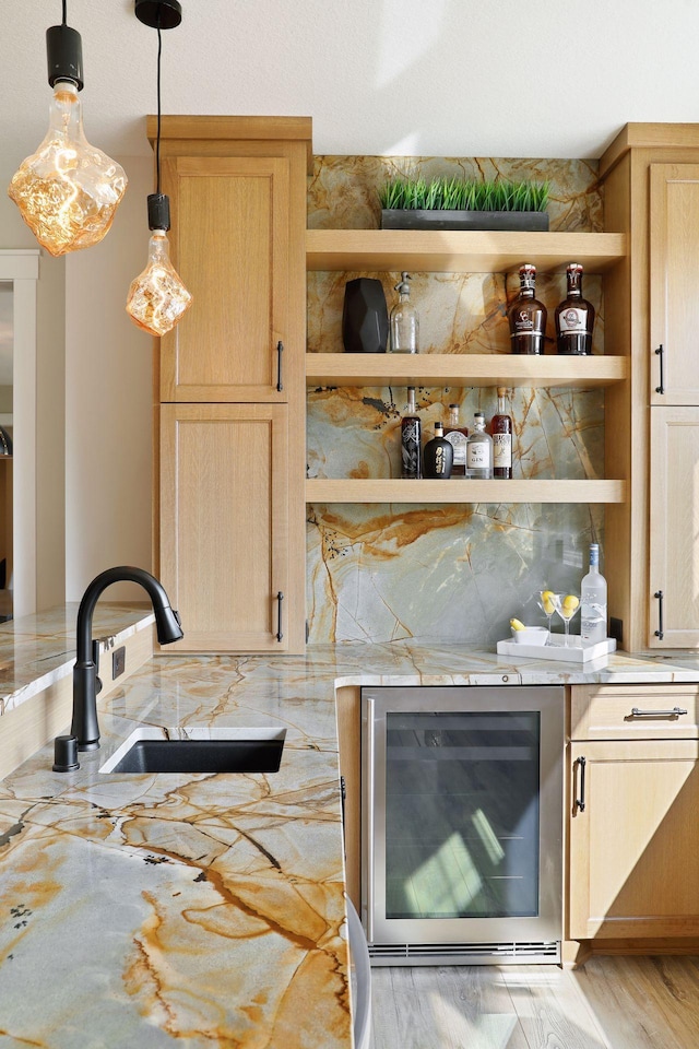 bar with hanging light fixtures, beverage cooler, sink, and light brown cabinets