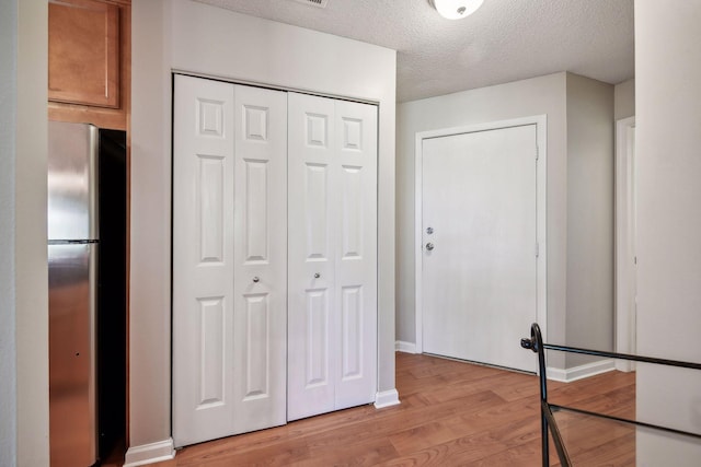 hall featuring light hardwood / wood-style floors and a textured ceiling