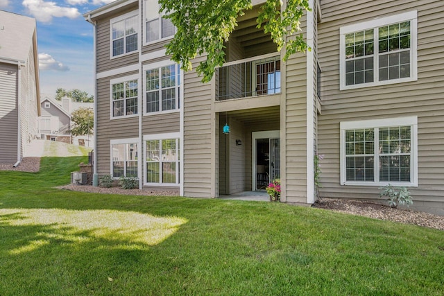 rear view of property featuring a lawn and central air condition unit