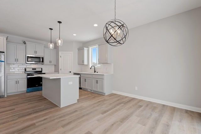 kitchen with stainless steel appliances, a kitchen island, decorative light fixtures, a chandelier, and sink