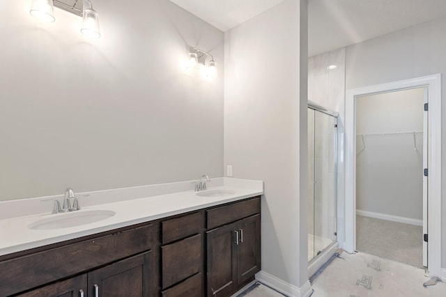 bathroom featuring a shower with shower door and vanity