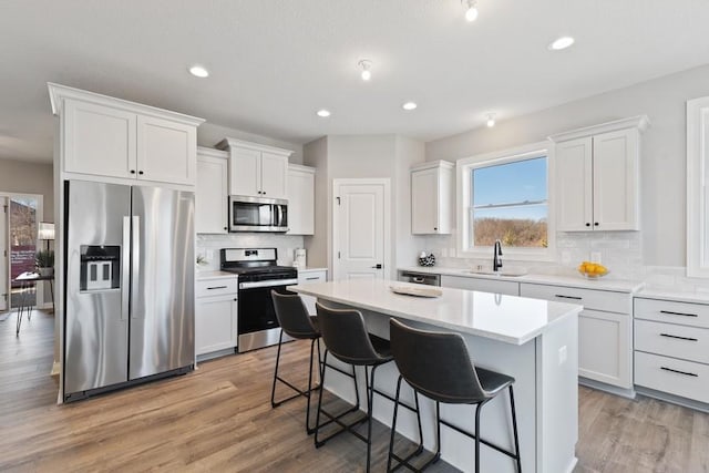 kitchen with a kitchen island, a breakfast bar area, stainless steel appliances, light wood-type flooring, and a sink