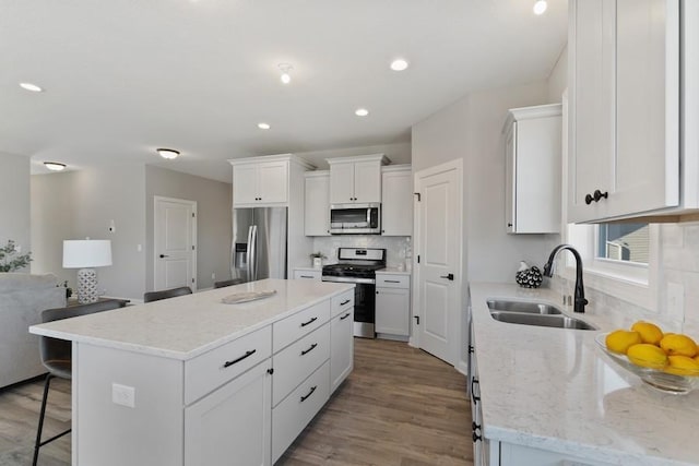 kitchen featuring a breakfast bar area, a kitchen island, a sink, appliances with stainless steel finishes, and tasteful backsplash