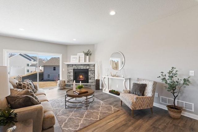 living area featuring visible vents, baseboards, wood finished floors, a stone fireplace, and recessed lighting