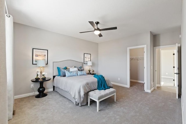 carpeted bedroom featuring a walk in closet, a closet, ceiling fan, and baseboards