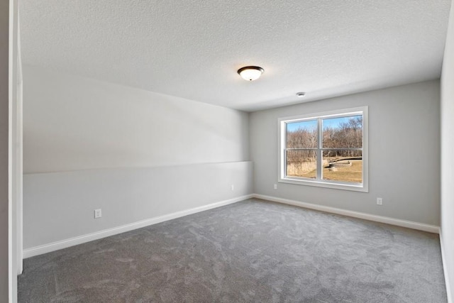 carpeted empty room with a textured ceiling and baseboards