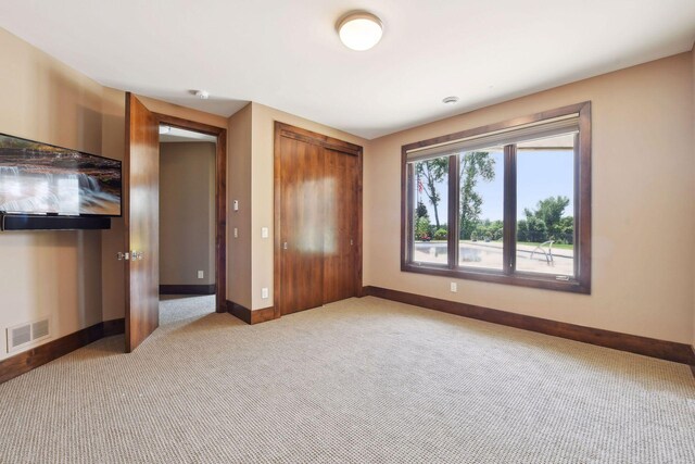 unfurnished bedroom featuring a closet and light colored carpet