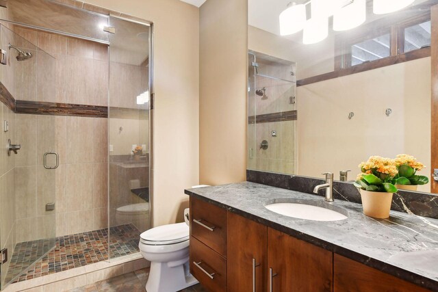 bathroom featuring a shower with shower door, vanity, tile patterned flooring, and toilet