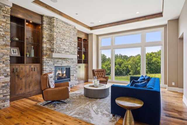 living room featuring a fireplace, a healthy amount of sunlight, hardwood / wood-style floors, and a tray ceiling