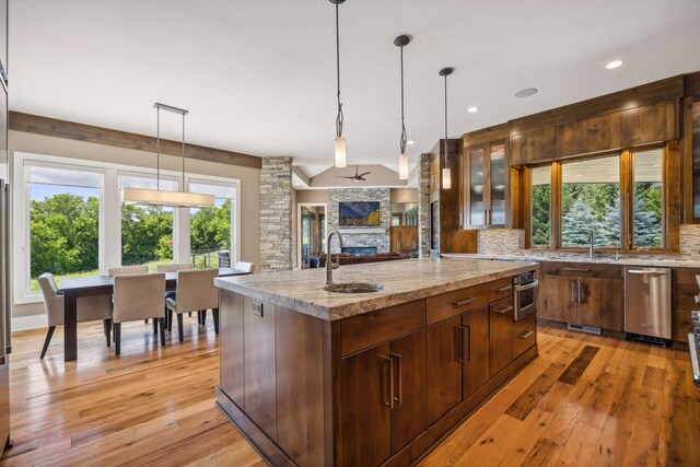 kitchen featuring light hardwood / wood-style flooring, a kitchen island with sink, stainless steel appliances, hanging light fixtures, and sink