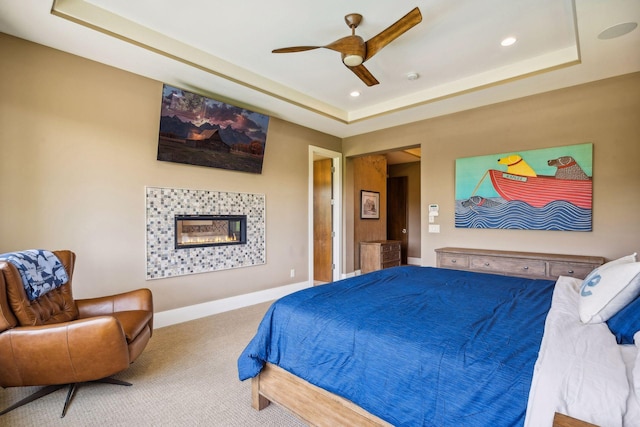 carpeted bedroom featuring ceiling fan and a tray ceiling