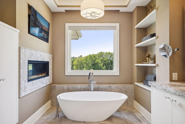 bathroom featuring vanity, tile patterned floors, a fireplace, and a tub to relax in