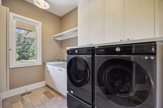 laundry area with sink, washer and dryer, cabinets, and light tile patterned floors