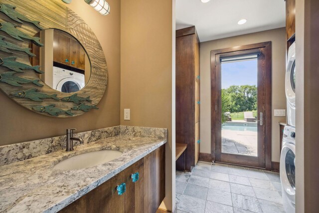 bathroom with stacked washer and clothes dryer, tile patterned floors, and vanity