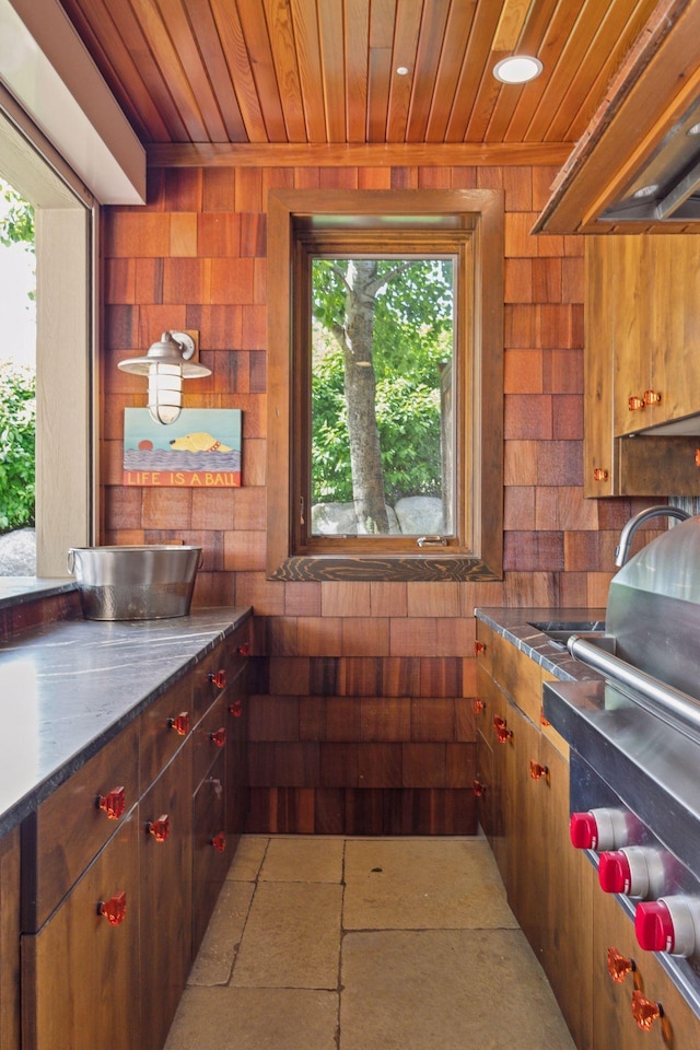 kitchen with a healthy amount of sunlight, wood walls, and custom range hood