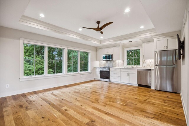 kitchen with white cabinets, a raised ceiling, light hardwood / wood-style flooring, and appliances with stainless steel finishes