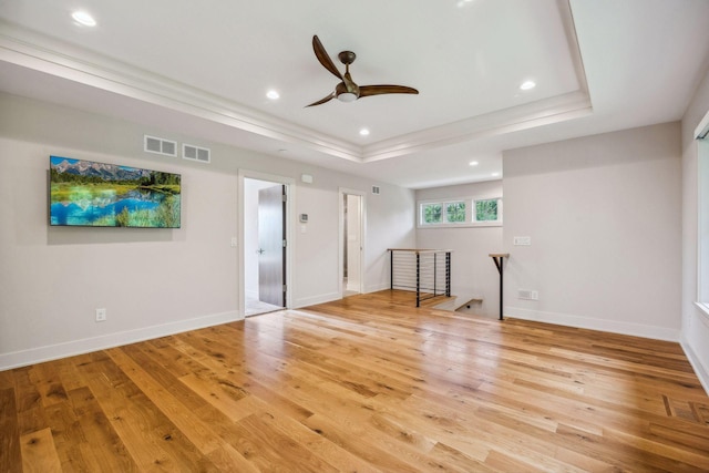 interior space with ceiling fan, light hardwood / wood-style floors, and a tray ceiling