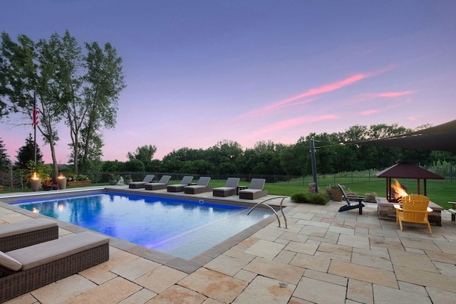 pool at dusk with a patio and a yard