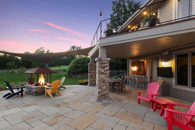 patio terrace at dusk featuring a lawn and a fire pit