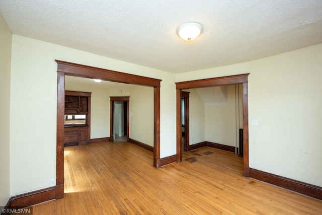 unfurnished room featuring light wood-type flooring and a textured ceiling