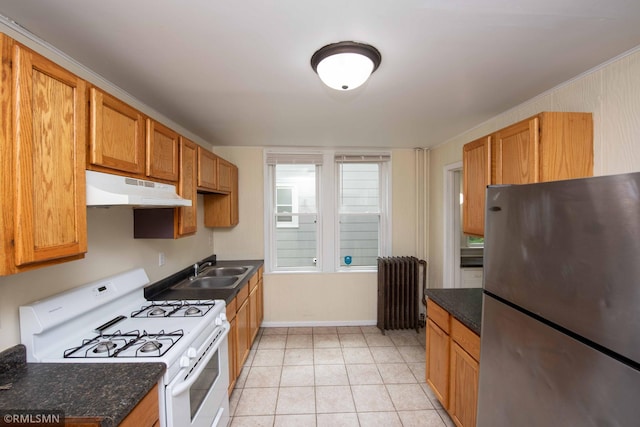 kitchen with sink, light tile patterned floors, white range with gas cooktop, radiator heating unit, and stainless steel fridge