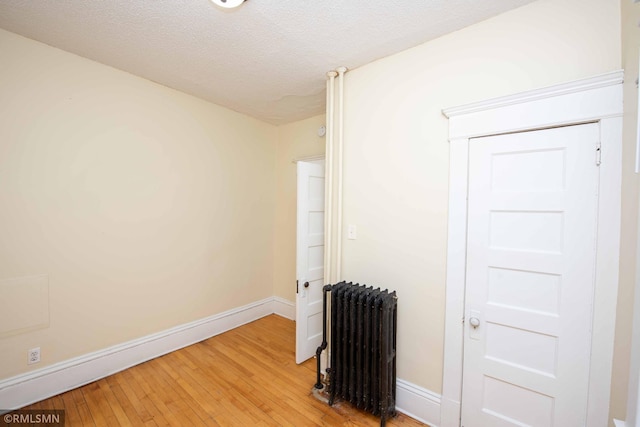 spare room with a textured ceiling, radiator heating unit, and hardwood / wood-style flooring