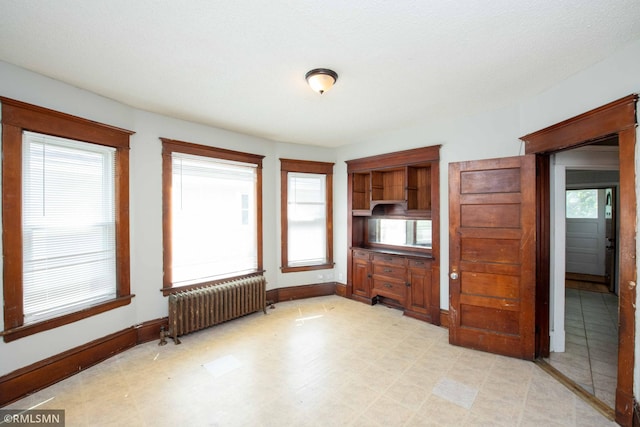 interior space featuring a textured ceiling, multiple windows, and radiator heating unit