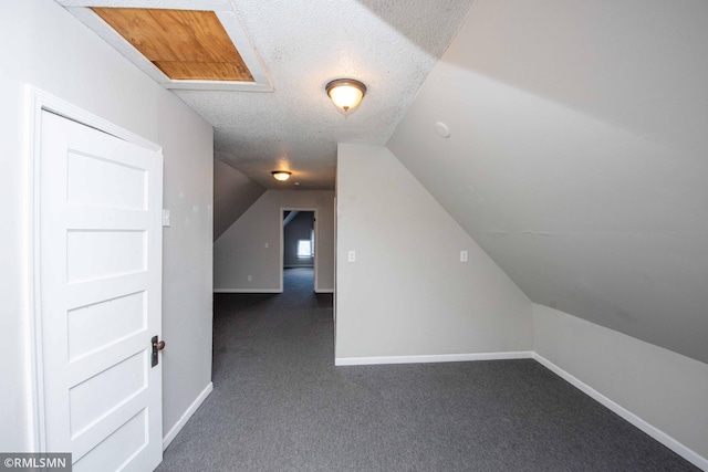 bonus room featuring a textured ceiling, lofted ceiling, and dark carpet