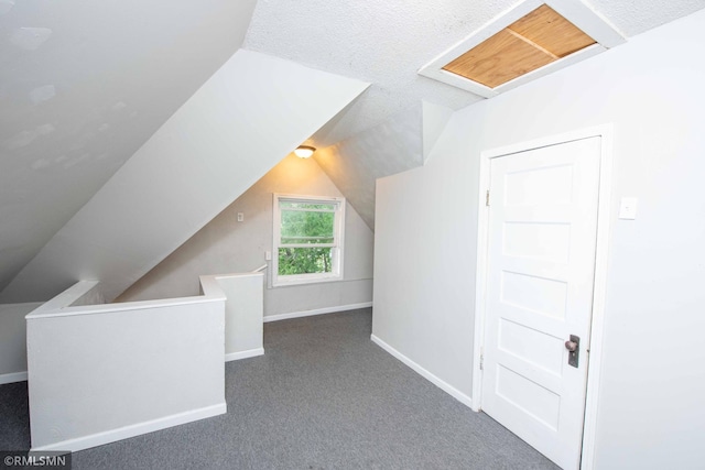 bonus room with dark carpet, lofted ceiling, and a textured ceiling