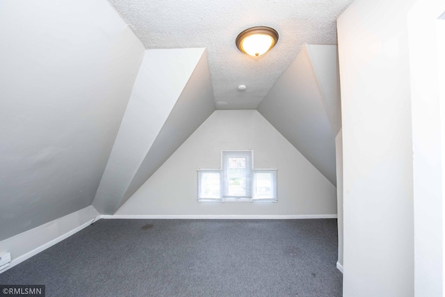 bonus room with a textured ceiling, lofted ceiling, and dark colored carpet