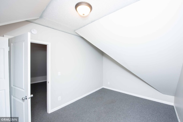 bonus room featuring dark carpet, a textured ceiling, and lofted ceiling