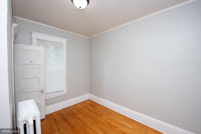 unfurnished room featuring crown molding, wood-type flooring, and radiator