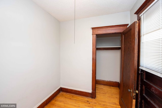 unfurnished bedroom featuring light wood-type flooring and a textured ceiling