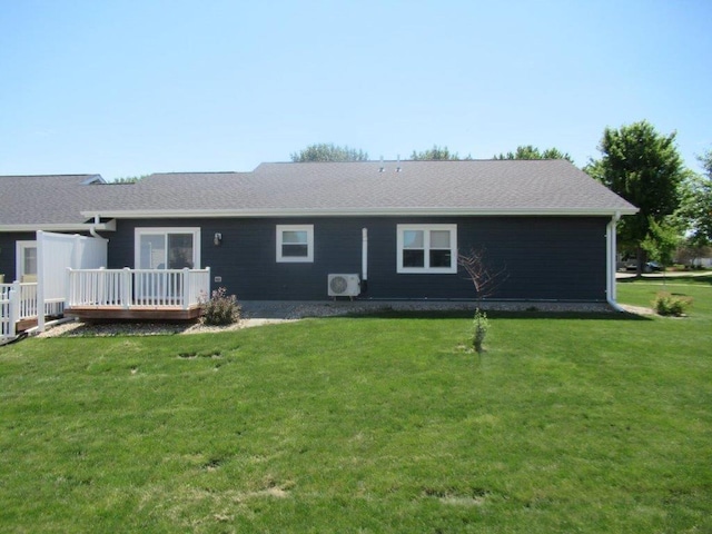 rear view of property with a shingled roof, a lawn, a wooden deck, and ac unit