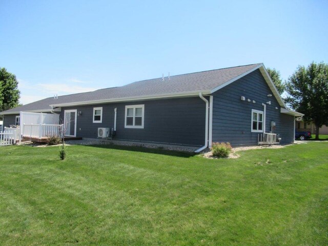 rear view of property with central AC and a yard